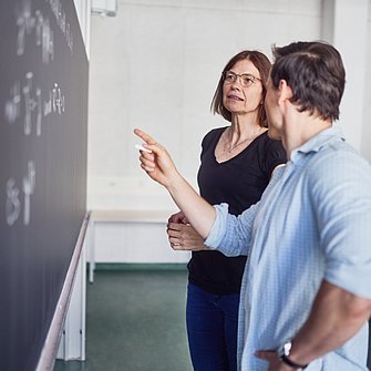 Instructor and Lerner discussing in front of a writing slate